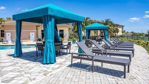 A poolside area with lounge chairs and a covered seating area. - Landing | Incredible 2BD, Courtyard, Yoga Studio (Fort Myers)