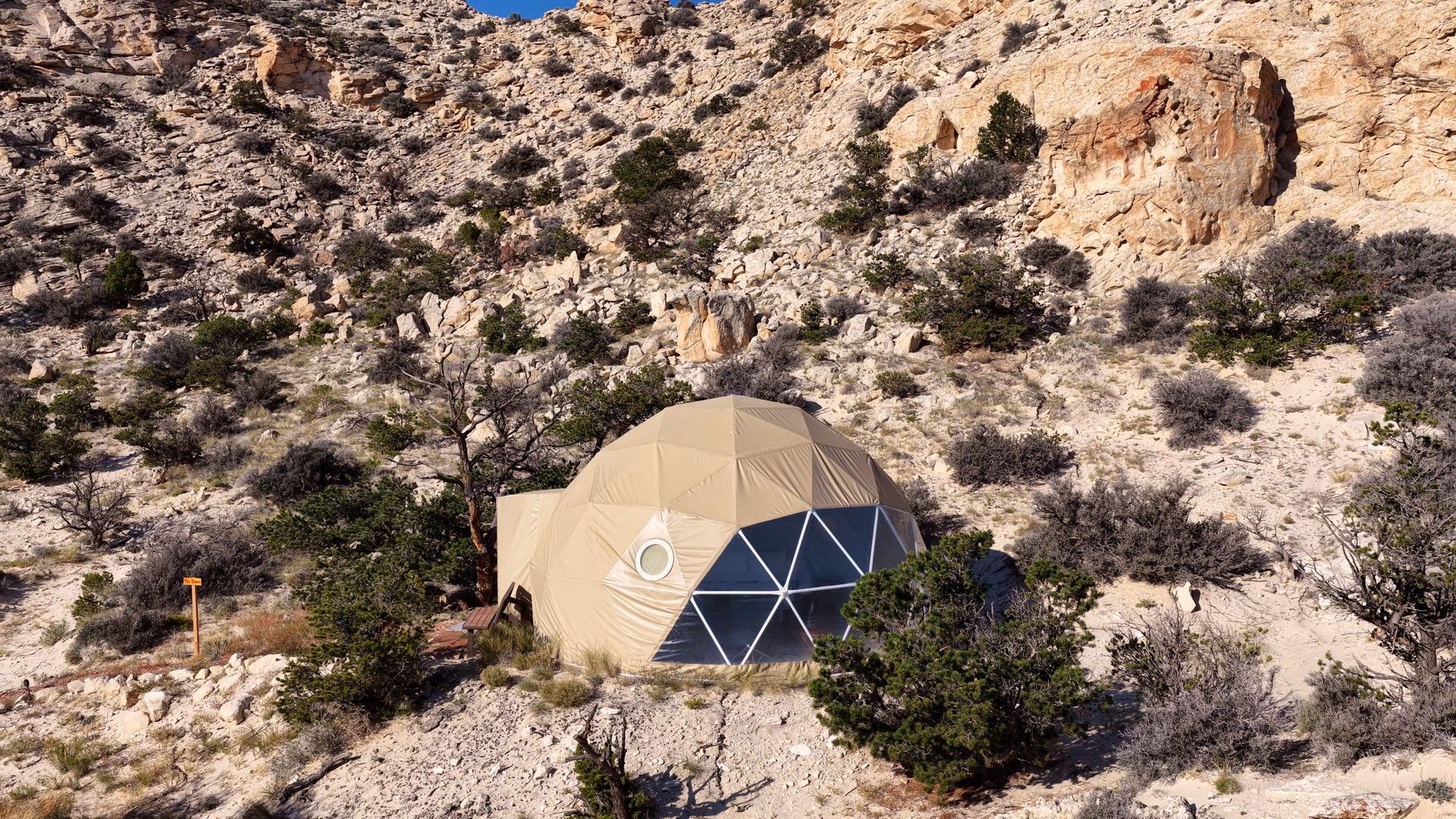 A dome-shaped structure in a rocky, desert-like environment with sparse vegetation.