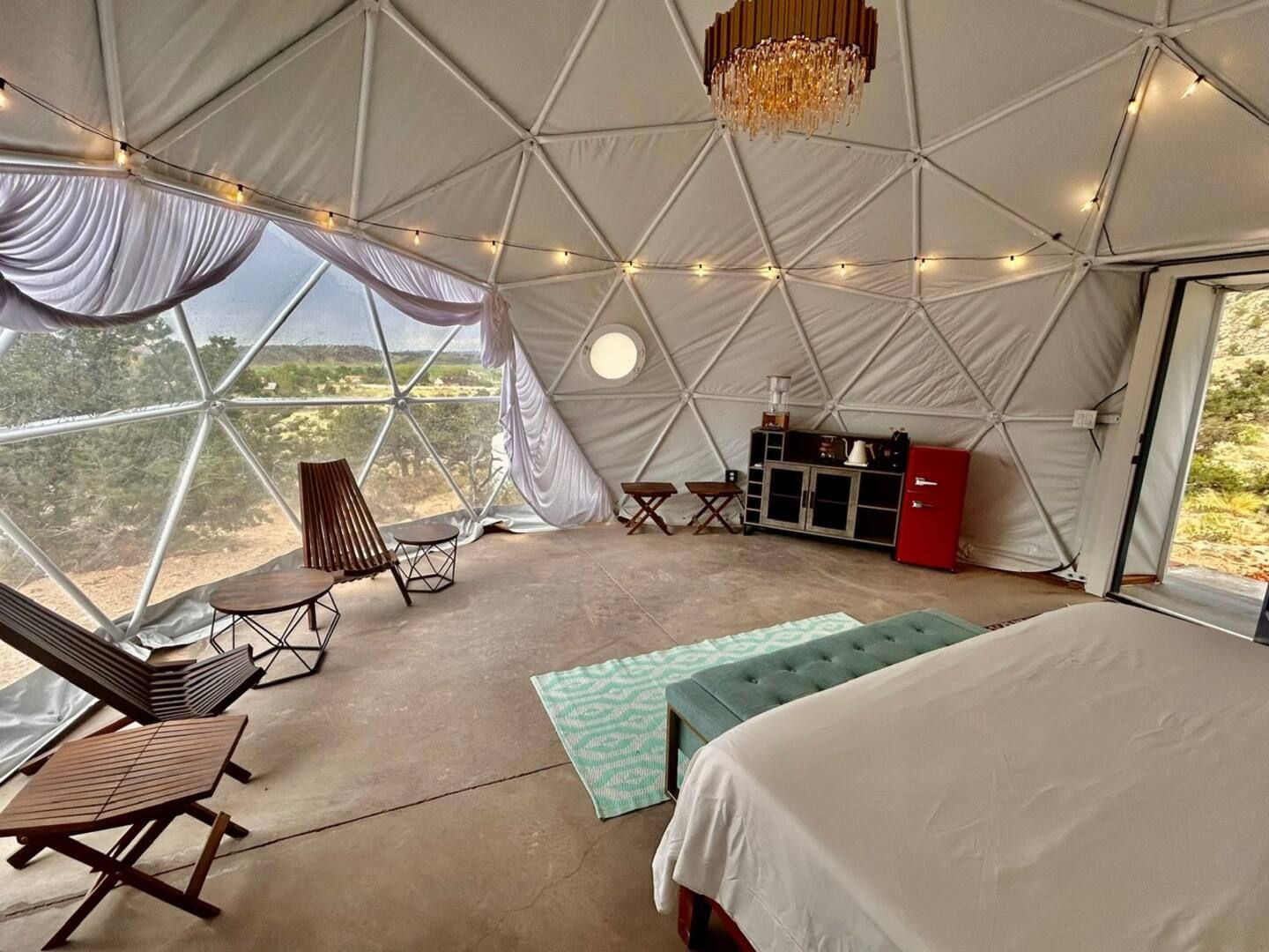 Uma tenda espaçosa com cama, área de estar e cozinha compacta.