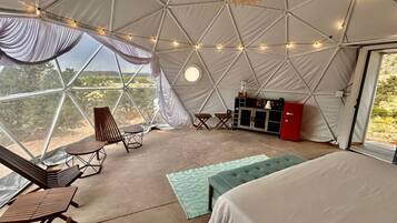 Uma tenda espaçosa com cama, área de estar e cozinha compacta.