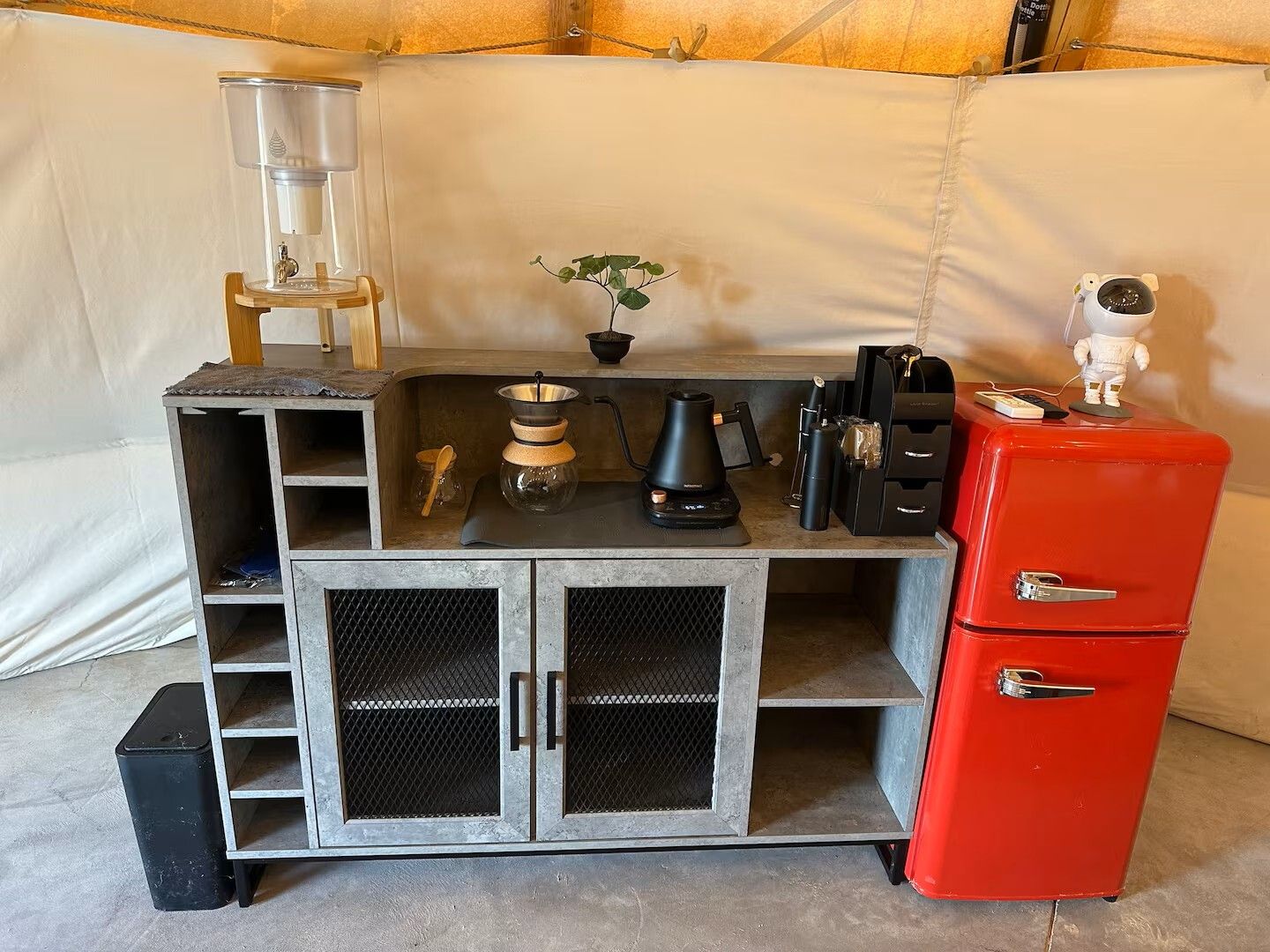 Eine Küchenzeile mit Kaffeemaschine, einer kleinen Pflanze und einem roten Kühlschrank.