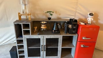 Eine Küchenzeile mit Kaffeemaschine, einer kleinen Pflanze und einem roten Kühlschrank.
