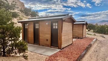A rustic cabin with two wooden doors, a metal roof, and a gravel driveway.