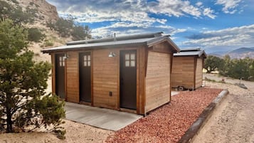 A rustic cabin with two wooden doors, a metal roof, and a gravel driveway.