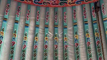 A room with a traditional design, featuring a patterned curtain and a view of the sky through a window.