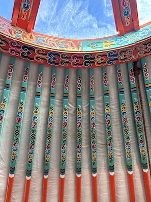 A room with a traditional design, featuring a patterned curtain and a view of the sky through a window.