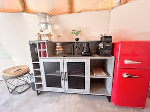 A kitchenette with a red refrigerator, a coffee maker, and a water dispenser.