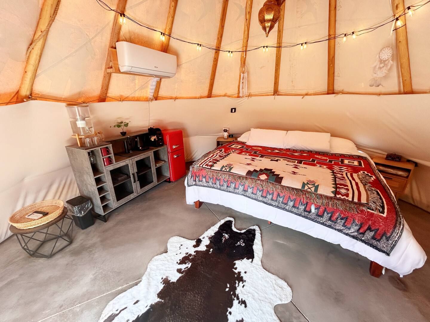Een gezellig interieur van een joert met een bed, een kleine kitchenette en een kluisje.