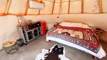 Een gezellig interieur van een joert met een bed, een kleine kitchenette en een kluisje.