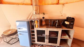 A compact kitchenette with a refrigerator, coffee maker, and storage cabinets.