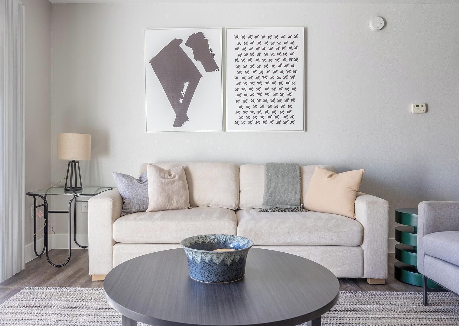 A modern living room with a sofa, a round coffee table, and two wall art pieces.