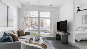 Un salon moderne avec un canapé, une table basse, un téléviseur et un lit.