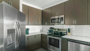 Una cocina moderna con electrodomésticos de acero inoxidable, gabinetes de madera oscura y azulejos blancos tipo metro.