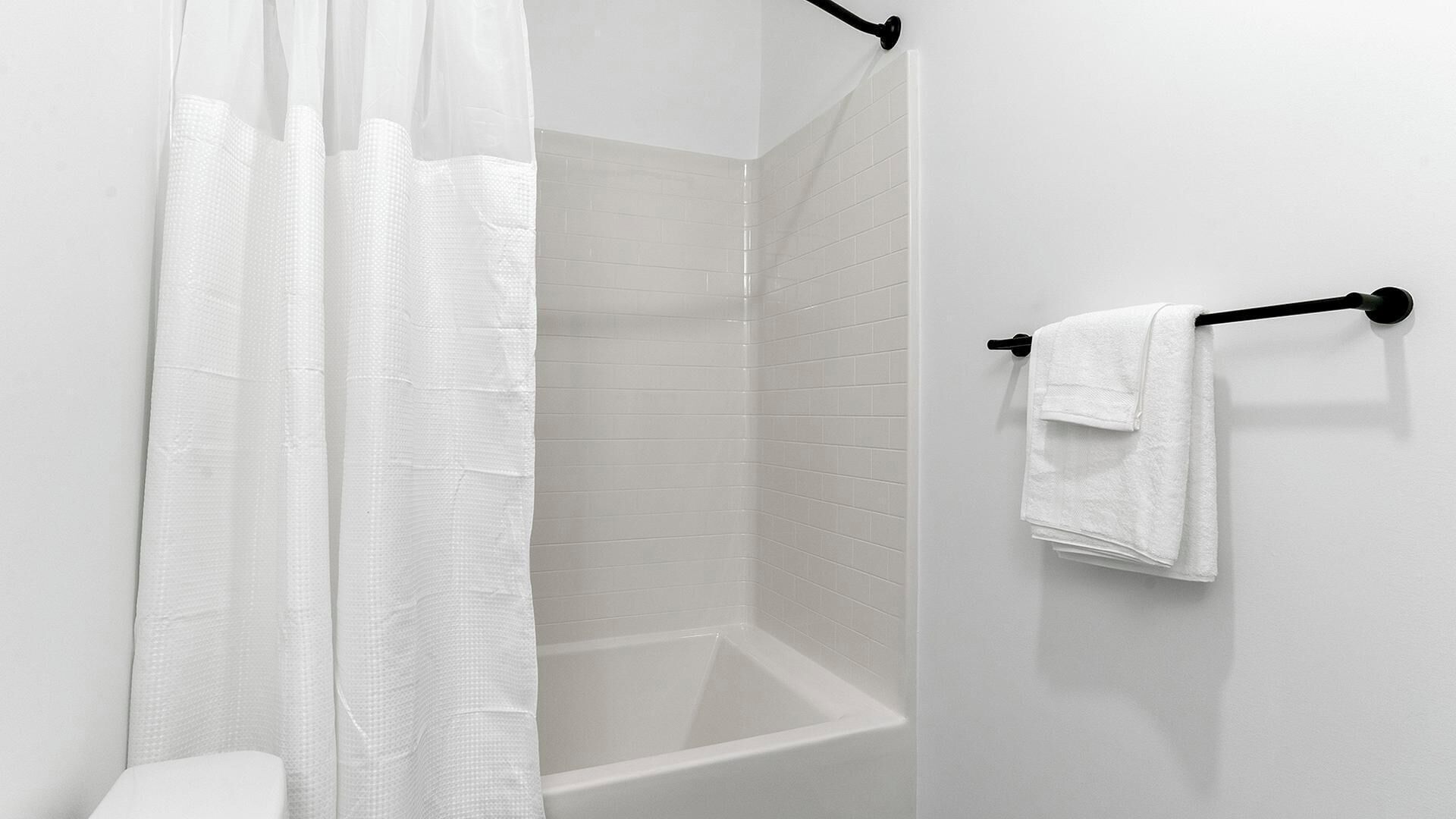 A bathroom with a shower, a bathtub, and a towel rack.