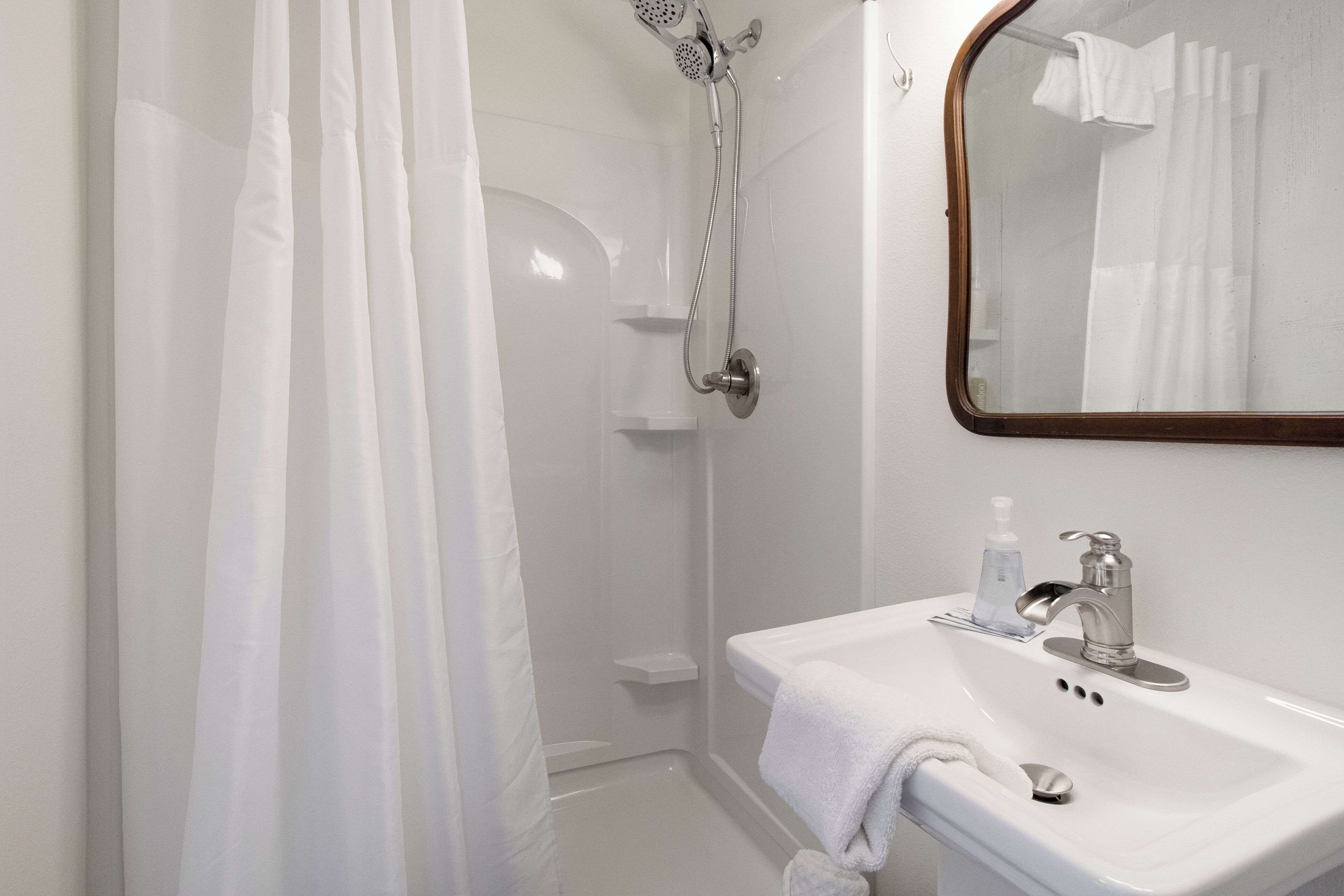 A bathroom with a shower, a sink, and a mirror.