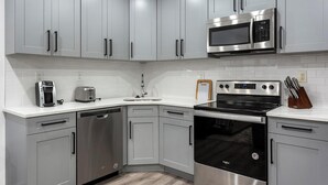 A modern kitchen with stainless steel appliances, white cabinetry, and a built-in oven. - Landing | Chic 2BD, Gym (Philadelphia)