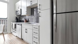 A modern kitchen with stainless steel appliances, a tiled backsplash, and a view of the city through the window.