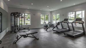 Ein modernes Fitnessstudio mit Cardiogeräten, Krafttrainingsgeräten und großen Fenstern mit Blick ins Freie.