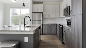 Una cocina moderna con una isla central, electrodomésticos de acero inoxidable y vistas al exterior a través de un amplio ventanal.