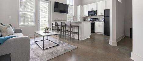 A modern apartment with a living room, kitchen, and dining area.