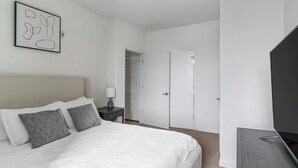 Une chambre à coucher comprenant un lit, une table de chevet, une lampe et une porte donnant sur un placard.