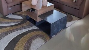 A modern living room with a sectional sofa, a coffee table, and a dining area in the background. - Spacious two bedroom home with ocean view, pool and tennis court. (Florence Hall Village)