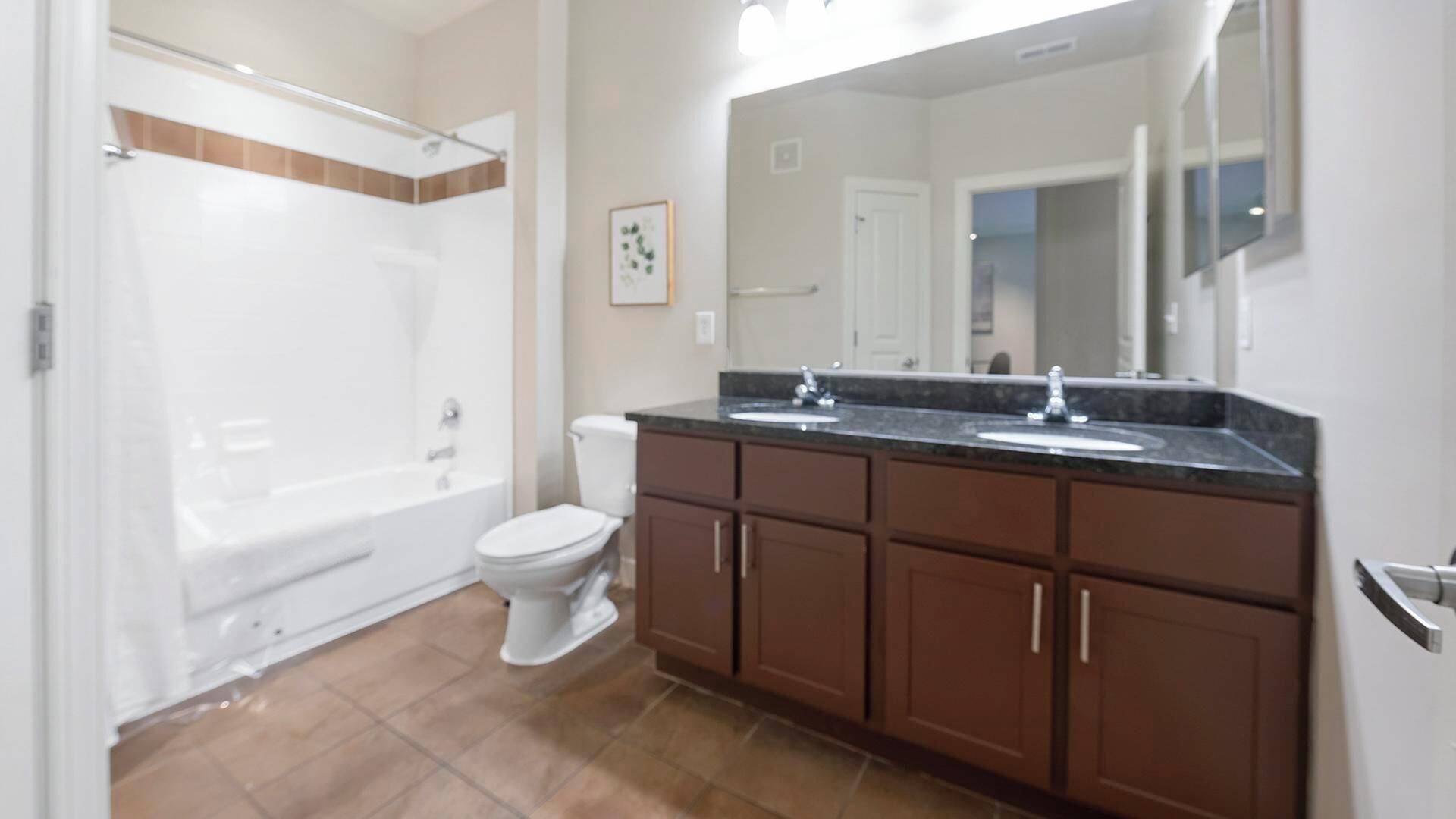 A bathroom with a bathtub, toilet, and vanity with a mirror.