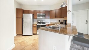 A modern kitchen with wooden cabinets, stainless steel appliances, and a granite countertop. - Landing | Stylish 1BD, Clubhouse, Courtyard (Hyattsville)