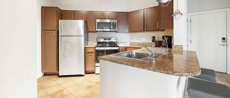 A modern kitchen with wooden cabinets, stainless steel appliances, and a granite countertop.