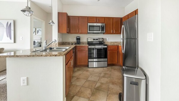 A modern kitchen with granite countertops, stainless steel appliances, and wooden cabinets.