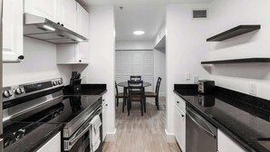A modern kitchen with white cabinets, black countertops, and a central island with chairs. - Modern UF Apartment ON Archer Rd Near Shands & VA (Gainesville)