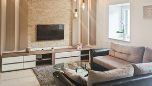 A living room with a flat-screen TV, a sofa, a coffee table, and a fireplace.