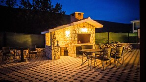 An outdoor patio with stone walls, a grill, and seating.