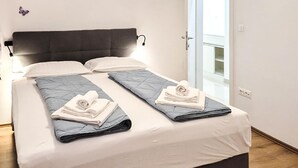 A double bed with a dark headboard, white linens, and folded towels.