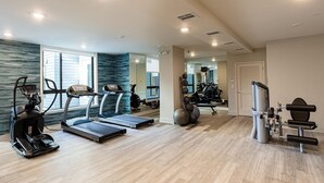 Un gimnasio moderno para el hogar con cintas de correr, pelotas de ejercicio y máquinas de pesas.