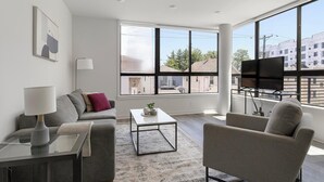 Een moderne woonkamer met een bank, fauteuil, salontafel en een televisie op een dressoir.