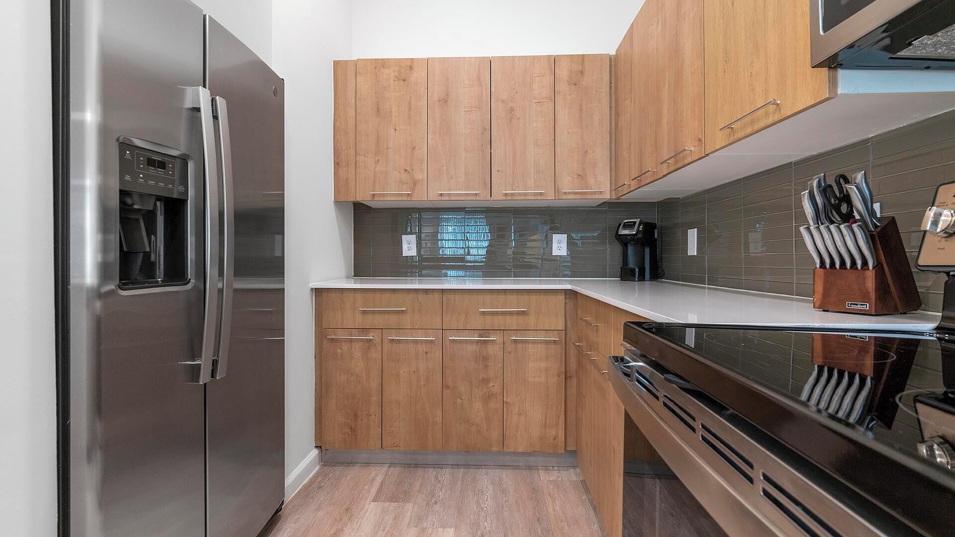 A modern kitchen with wooden cabinets, stainless steel appliances, and a black stove.
