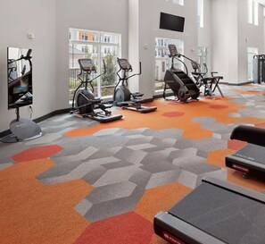 Une salle de sport équipée de tapis de course, de vélos d’appartement et d’appareils de musculation.