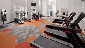 Een fitnessruimte met loopbanden, hometrainers en krachtapparaten.