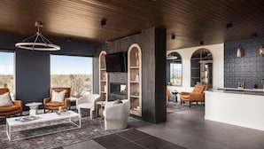 Una sala de estar moderna con chimenea, asientos cómodos y un amplio ventanal con vistas.