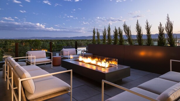 Una terraza en la azotea con un brasero, asientos al aire libre y vistas de la ciudad.