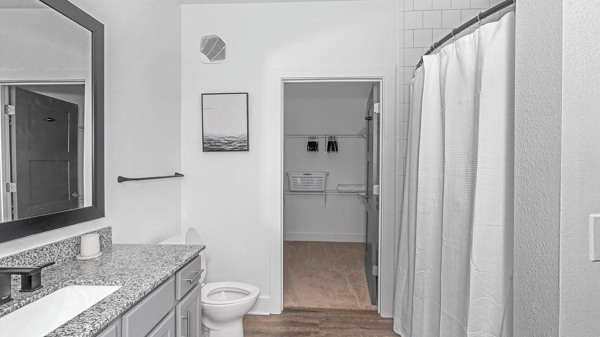 Une salle de bain avec un comptoir en granit, des toilettes, un rideau de douche et un porte-serviettes.