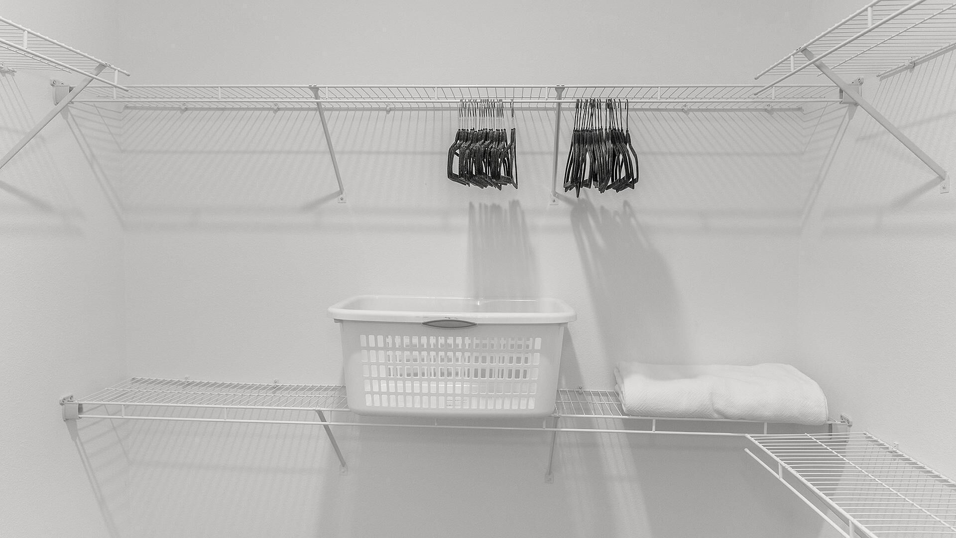 A laundry room with a drying rack, a basket, and hanging clothes.
