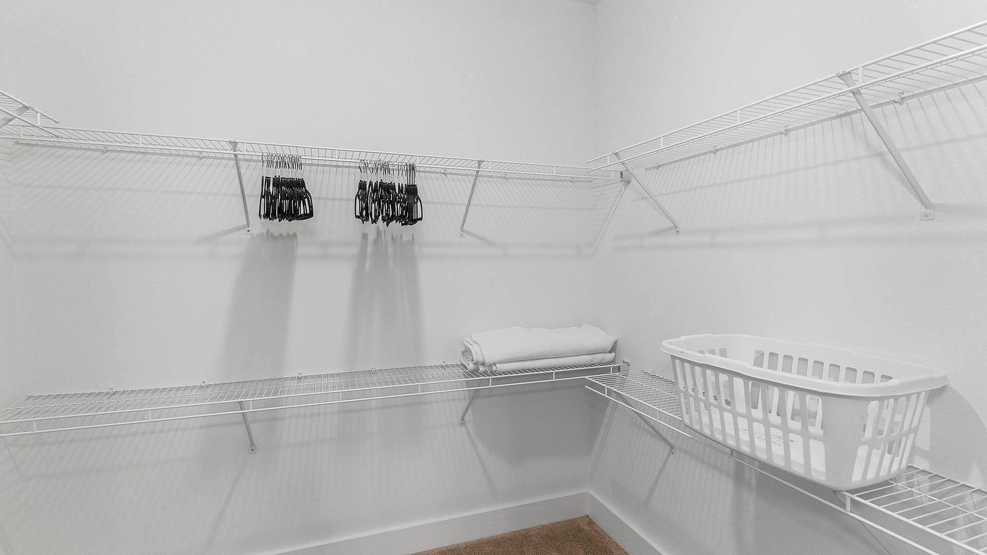 A white-walled room with a crib, a white towel, and a metal shelf with hanging items.