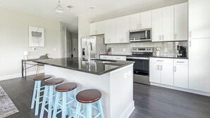 A modern kitchen with white cabinets, stainless steel appliances, and a central island with stools.