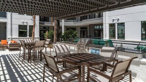 Une terrasse extérieure équipée d’un barbecue, d’un espace salon et offrant une vue sur la façade du bâtiment.