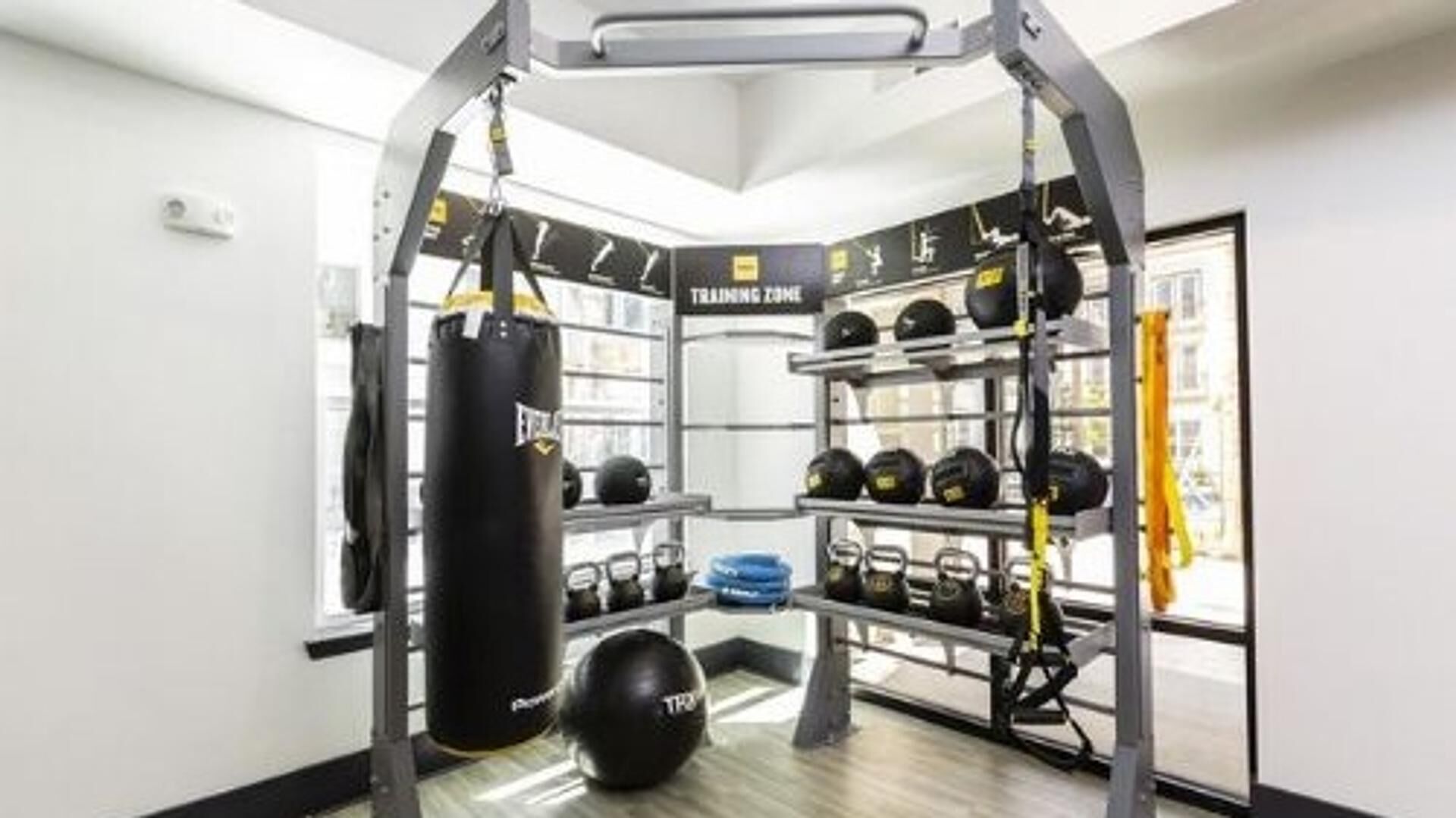 A gym with a pull-up bar structure, weight plates, and a punching bag.