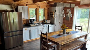 A rustic kitchen with wooden cabinets, a stainless steel refrigerator, and a wooden dining table with chairs.