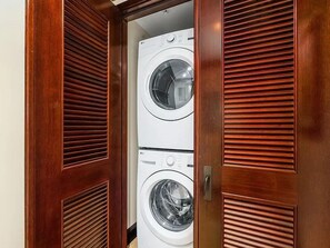 A wooden wardrobe with two white front-loading washing machines inside.