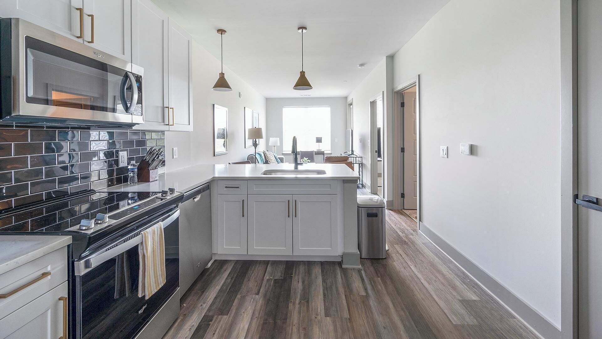 Une cuisine moderne dotée d’un îlot central, d’appareils électroménagers en acier inoxydable et d’un plancher en bois.